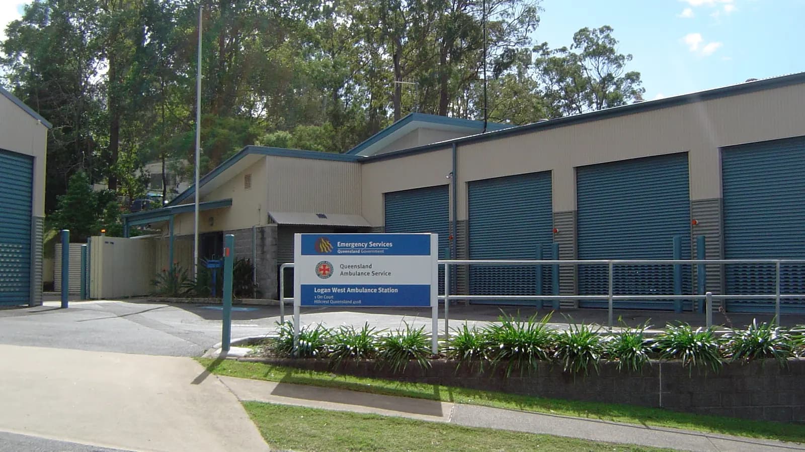 An Australian ambulance station with roller doors and a service sign at the roadside