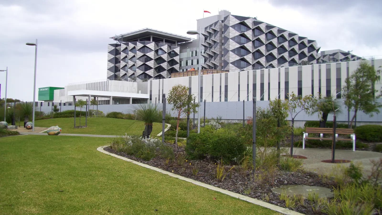 A large modern hospital with a patterned facade, seen across its landscaped grounds