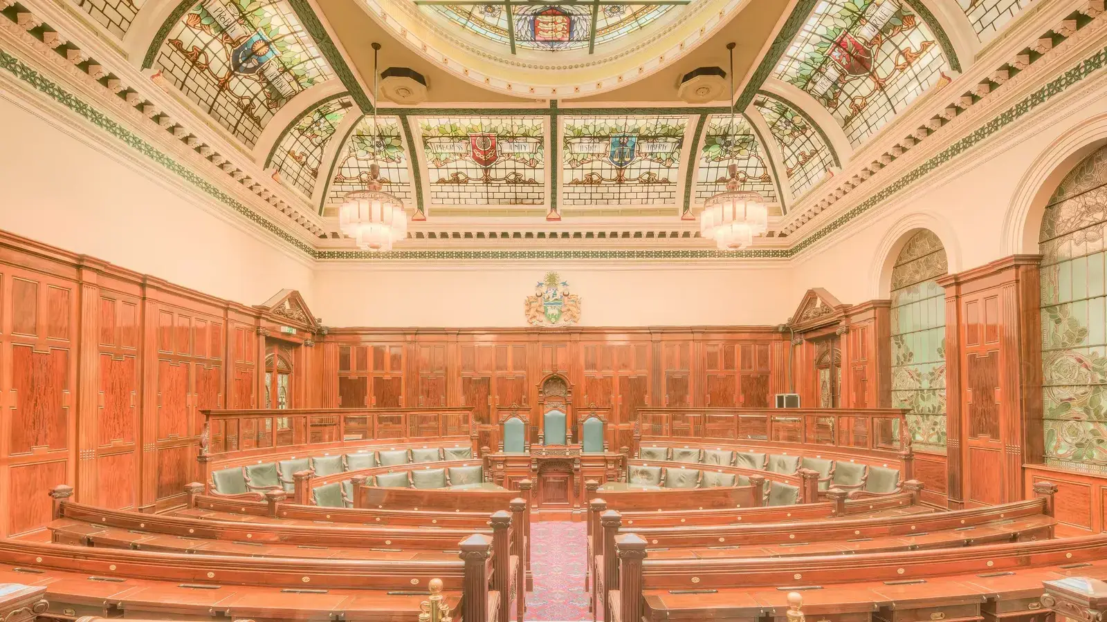 The council chamber at Halifax Town Hall, ranks of wooden benches curving towards a raised seat