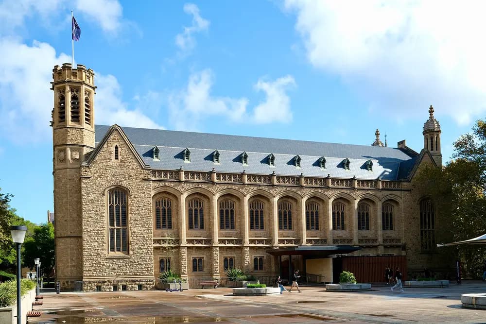 Bonython Hall, the iconic gothic sandstone great hall of the University of Adelaide on North Terrace, Adelaide, Australia, under a bright blue daytime sky.