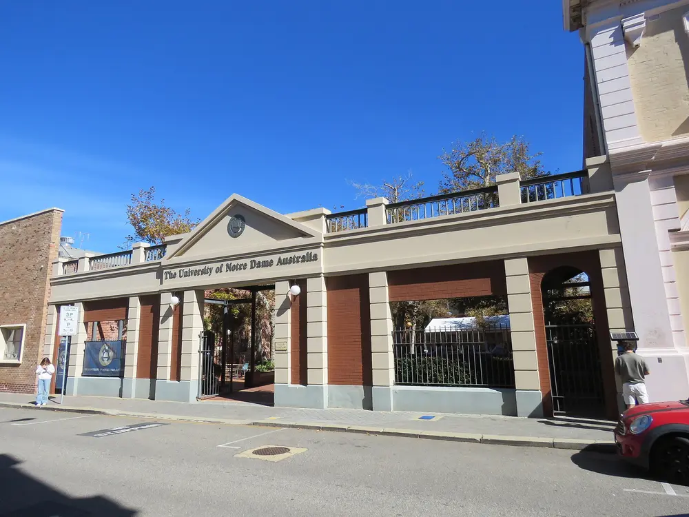 The named main entrance gateway of the University of Notre Dame Australia, Fremantle campus, reading "The University of Notre Dame Australia" under a bright blue sky.