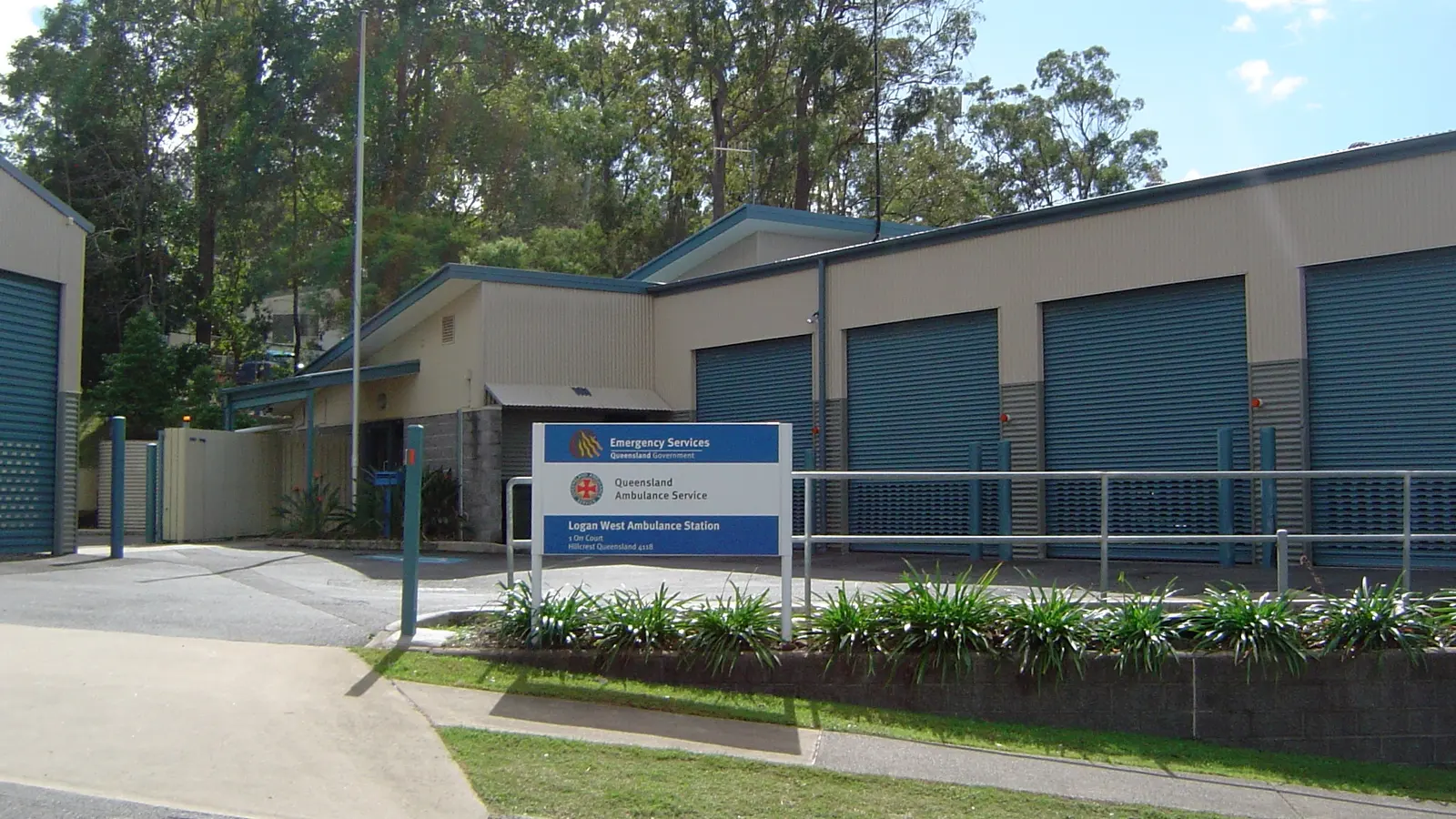 An Australian ambulance station with roller doors and a service sign at the roadside